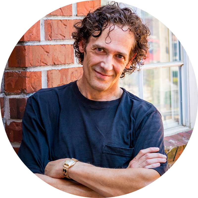 Portrait of Dr. Kevin J. Payne, smiling, arms folded, standing against a brick wall.