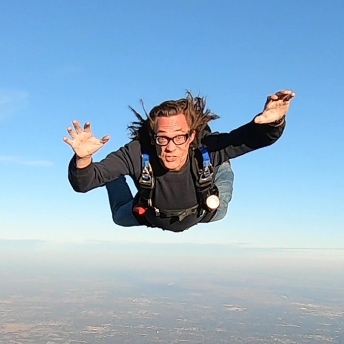 Dr. Kevin J. Payne in freefall against a blue sky, arms spread