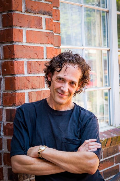 Dr. Kevin J. Payne, arms crossed, leaning against a brick wall